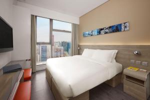 um quarto de hotel com uma cama grande e uma janela grande em Lodgewood by Nina Hospitality Mong Kok em Hong Kong