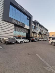 a parking lot with cars parked in front of a building at Sokon Ladn Hotel in Riyadh