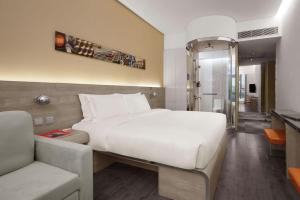 - une chambre avec un grand lit blanc et un canapé dans l'établissement Lodgewood by Nina Hospitality Mong Kok, à Hong Kong