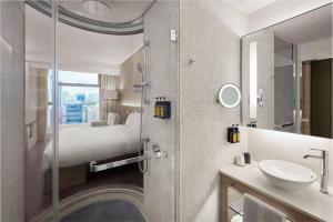 um banheiro com uma cama, uma pia e um espelho em Lodgewood by Nina Hospitality Mong Kok em Hong Kong