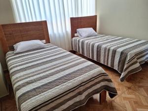 dos camas sentadas una al lado de la otra en una habitación en Hospedaje por departamentos UVIMA III en Cusco