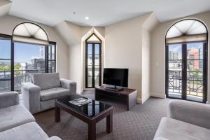 uma sala de estar com um sofá e uma televisão em Frome Apartments em Adelaide