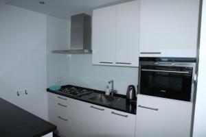 uma cozinha branca com um lavatório e um fogão em Berrie's Sea View em Zandvoort