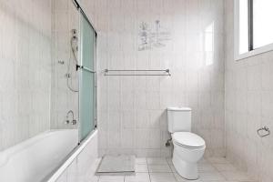 a bathroom with a toilet and a tub and a shower at Cozy Bankstown Stayz in Bankstown