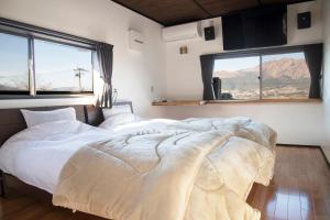 dwa łóżka w pokoju z dwoma dużymi oknami w obiekcie お宿でん吉 w mieście Minami Aso