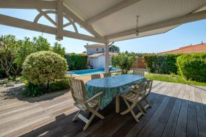 un patio con mesa y sillas en una terraza de madera en Magnifique Villa Avec Jardin Proche De La Plage, en Arès