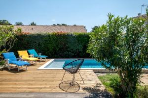una silla sentada en una terraza de madera junto a una piscina en Magnifique Villa Avec Jardin Proche De La Plage, en Arès