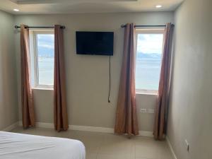 a bedroom with two windows and a television on the wall at Beach access apartment in Portmore
