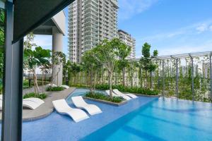 a swimming pool with white chairs and a building at Highpark Suites at Petaling Jaya, Kelana Jaya by Plush in Petaling Jaya