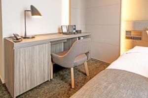 a bedroom with a desk with a chair and a bed at Hotel JAL City Fukuoka Tenjin in Fukuoka