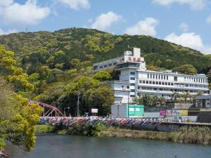 Ein Zug parkt vor einem Gebäude neben einem Fluss in der Unterkunft Hotel Ryutouen in Saga