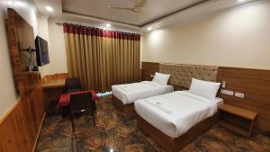 um quarto de hotel com duas camas e uma secretária em Nomadic Inn em Dharamshala