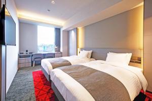 two beds in a hotel room with a desk at Hotel JAL City Fukuoka Tenjin in Fukuoka