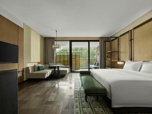 a hotel room with a large bed and a living room at Banyan Tree Dongguan Songshan Lake in Dongguan