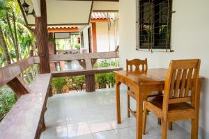 Lanta School Beach Resort في Phra Ae beach: طاولة خشبية وكرسي على شرفة مطلة على الفناء