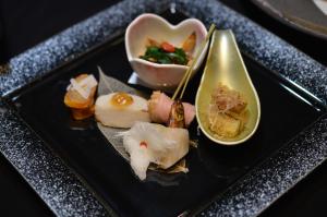 a black plate with sushi and a bowl of food at Tokachigawa Moor Onsen Seijyakubow in Otofuke