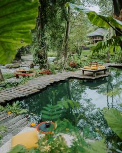 eine Holzbrücke über einen Teich mit zwei Booten darauf in der Unterkunft Bambu Indah in Ubud
