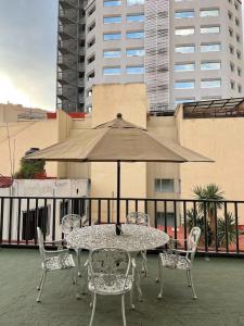a table and chairs with an umbrella on a balcony at NIce & cozy apt in San José Ins. in Mexico City
