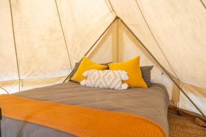 a bed with yellow pillows in a tent at Coonamble Riverside Caravan Park in Coonamble