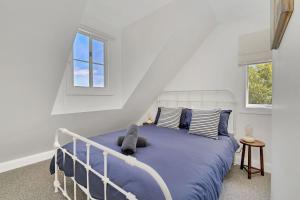 1 Schlafzimmer mit einem Bett mit blauer Bettwäsche und 2 Fenstern in der Unterkunft Cherry Tree Cottage, Burrawang, Southern Highlands in Burrawang