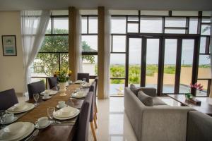 comedor con mesa, sillas y ventanas en Jimbaran Sea View Villa, en Jimbaran