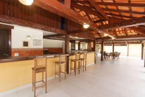 a bar in a room with wooden ceilings and wooden stools at Búzios casa em condomínio com cozinha completa e área gourmet in Búzios
