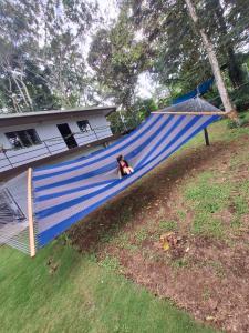 a woman sitting on a blue hammock in a yard at Hotel Azul Coral in Cahuita