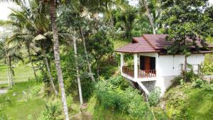 a small white house in the middle of trees at Nea Cottage Lombok in Tetebatu
