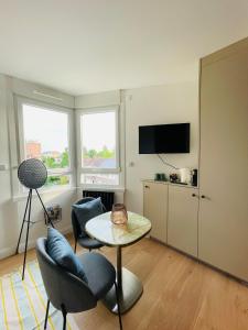een woonkamer met een tafel en stoelen en een televisie bij Lille / Marcq Au cœur du Croisé Laroche in Marcq-en-Baroeul