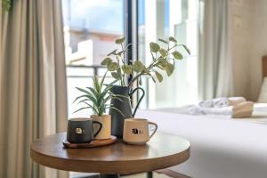 2 tasses à café sur une table en bois avec une plante dans l'établissement Apartment Hotel 11 Kuromon II, à Osaka