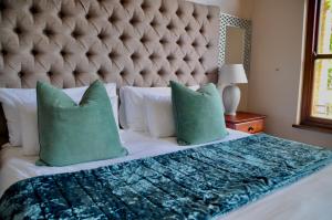a bedroom with a large bed with green pillows at Ambonnay Terrace Guest House in Pretoria