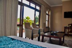 ein Hotelzimmer mit einem Bett, Stühlen und einem Fenster in der Unterkunft Ambonnay Terrace Guest House in Pretoria