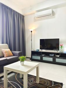 a living room with a couch and a tv at Luxury Comfort Suite 3BR in Jelutong