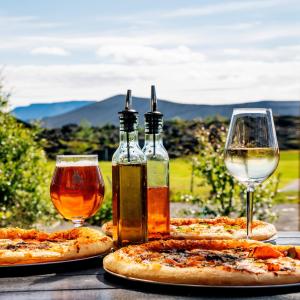 uma mesa com três pizzas e dois copos de vinho em Vogar Travel Service em Myvatn