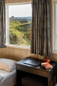 ein Schlafzimmer mit einem Fenster und einem Schreibtisch mit einem Laptop in der Unterkunft Vogar Travel Service in Mývatn