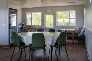 a dining room with a large table and green chairs at Vogar Travel Service in Myvatn