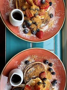 two plates of food with berries and powdered sugar at Brightham House in Salcombe