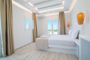 a white bedroom with a bed and a window at Depis Edem private villas naxos in Plaka