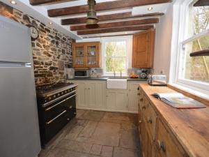 a kitchen with wooden cabinets and a stone wall at 3 Bed in Aberaeron 55308 in Ciliau-Aeron