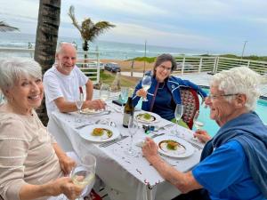 a group of people sitting at a table eating food at Bentley on the Beach in Umhlanga