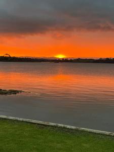 Clarks Beach的住宿－Absolute Waterfront Serenity Near Auckland，日落在水体上,日落在太阳下