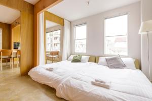 uma grande cama branca num quarto com janelas em Hotel Re:ONcE Shibuya em Tóquio