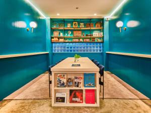 Habitación con paredes azules y mesa con libros. en Prince Theatre Heritage Stay Hostel - Silom en Bangkok