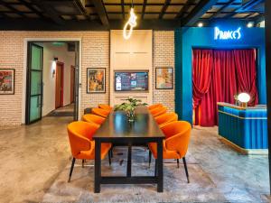 a dining room with orange chairs and a table at Prince Theatre Heritage Stay Hostel - Silom in Bangkok