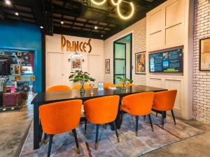 een eetkamer met een tafel en oranje stoelen bij Prince Theatre Heritage Stay Hostel - Silom in Bangkok