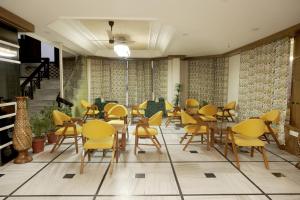 un restaurant avec des chaises et des tables jaunes dans une pièce dans l'établissement Hotel Bhawani International, à Katra