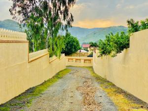 uma estrada de terra entre duas cercas com montanhas ao fundo em Udai Nature Valley Resort by AN Hotels-A Peacefull river Retreat em Udaipur