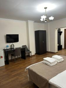 a room with a bed and a desk and a television at Skif Hotel in Astana