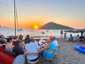 eine Gruppe von Menschen, die am Strand sitzen und den Sonnenuntergang beobachten in der Unterkunft Paradise Gümüşlük in Gümüşlük