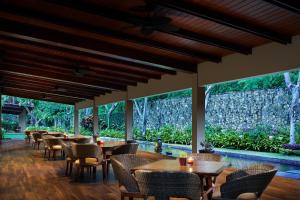 a restaurant with tables and chairs and large windows at eL Hotel Banyuwangi in Banyuwangi